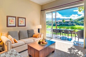 A living room with a sofa, coffee table, and a view of a golf course through large windows.
