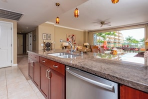 A modern kitchen with granite countertops, stainless steel appliances, and a large window overlooking a pool area.