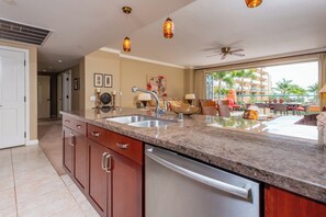A modern kitchen with granite countertops, stainless steel appliances, and a large window overlooking a pool area.