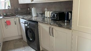 A compact kitchen with a washing machine, a coffee maker, and a toaster. - Lavish 3 story house : Double Room with Shared Toilet (Dagenham)