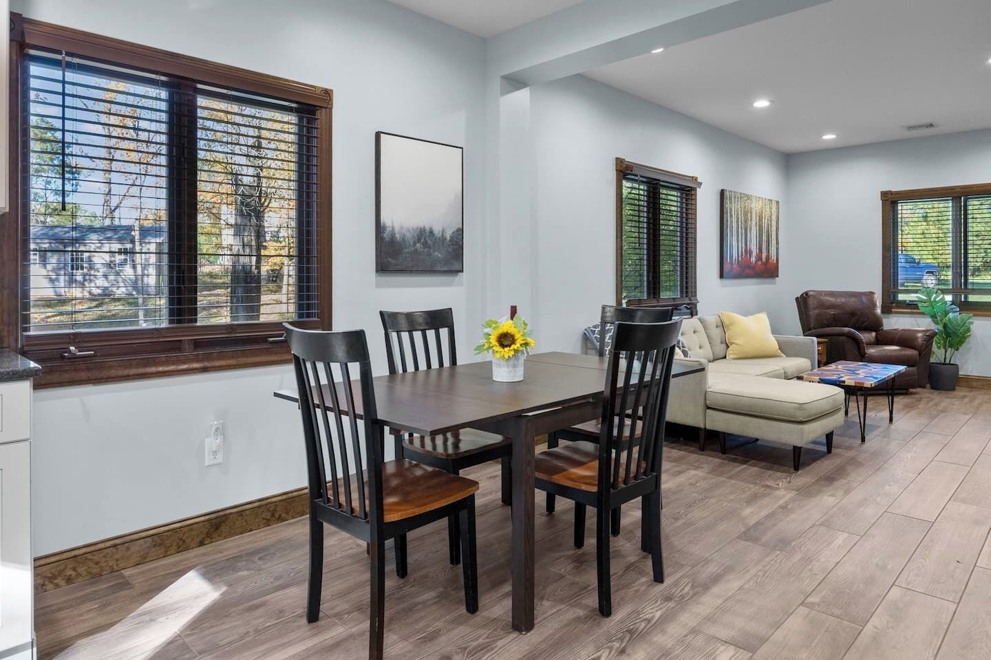 A modern living room with a dining area, featuring a wooden dining table, chairs, a sofa, and a coffee table.