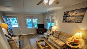 A spacious living room with a ceiling fan, two sofas, a coffee table, and a television. - Escape to our charming waterfront beach house in Beach Haven, just steps from the shore. This 3-bedroom retreat offers stunning bay views and a cozy atmosphere for a peaceful coastal getaway. Perfect for families, your ultimate vacation awaits!! (Beach Haven)