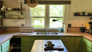 Una cocina con una mesa de madera, armarios verdes, una ventana y un lavamanos.