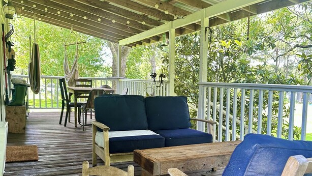 Un espacio al aire libre cubierto con mobiliario de madera, incluyendo un sofá, sillas y una mecedora.
