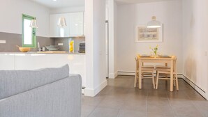 Een moderne keuken met witte kastjes, een eettafel met stoelen en hanglampen.