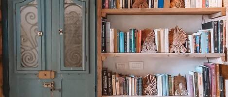 Een rustieke kamer met een blauwe deur, boekenplanken, decoratieve objecten en rieten manden.