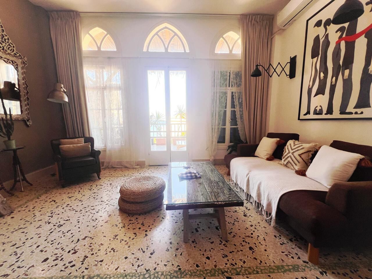 A living room with a sofa, a table, a chair, and a decorative wall piece.