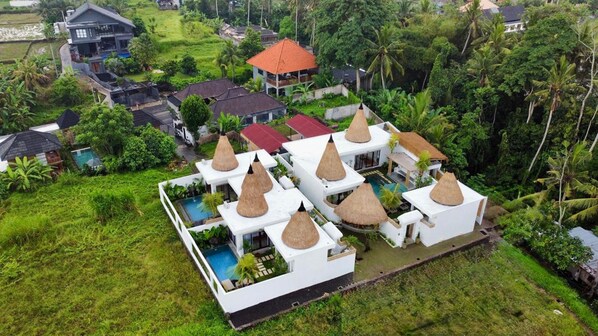 A resort with multiple bungalow-style buildings, each with a thatched roof and a swimming pool. - Golden Bee (Mas)