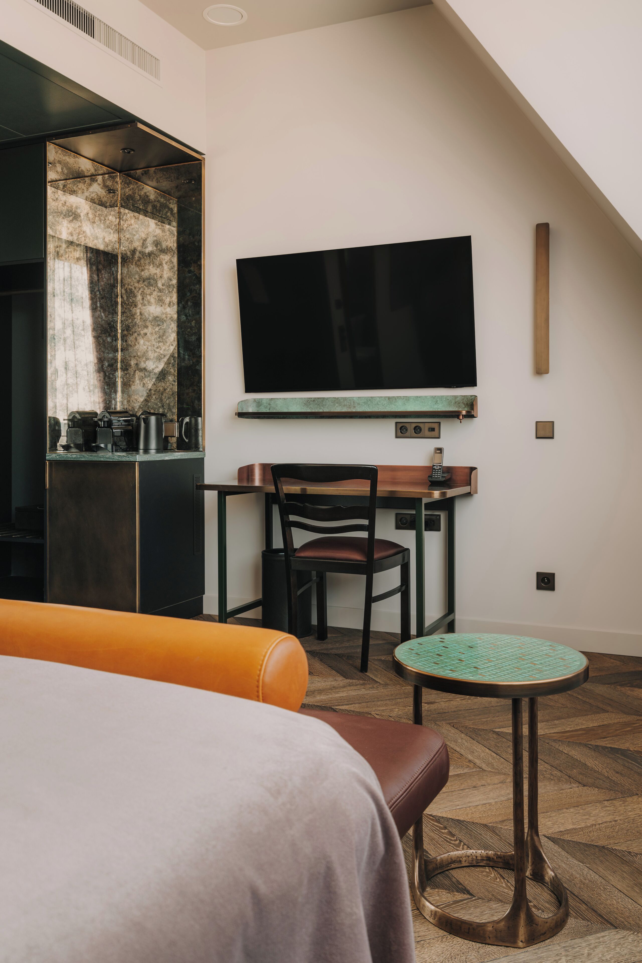 Una moderna camera d'albergo con un letto grande, un tavolino con una sedia, una TV a parete e un angolo cottura.