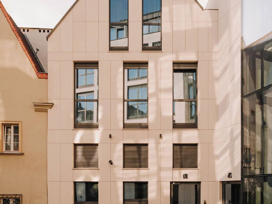 Un bâtiment moderne doté d’un toit plat, de nombreuses fenêtres et d’un patio en briques avec un espace aménagé pour s’asseoir à l’extérieur.