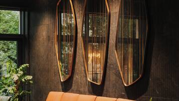 A modern interior with a leather sofa, large mirrors, and potted plants.