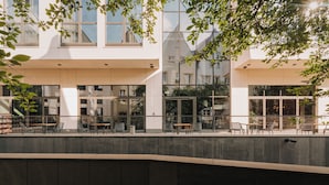 Un bâtiment moderne doté de grandes fenêtres, d’une terrasse et d’un mur incurvé.