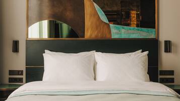 A hotel room with a large bed, a modern abstract painting on the wall, and a nightstand with a lamp.