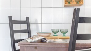 Une cuisine avec une table en bois, deux chaises, un saladier et deux bols en verre, ainsi qu’un magazine.