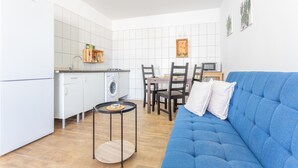 Une cuisine moderne équipée d’un lave-linge, un coin repas avec des chaises et une table, et un canapé bleu.