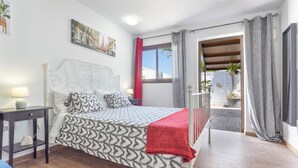 Une chambre à coucher avec un lit, une table de chevet, une fenêtre et une vue sur l’extérieur.