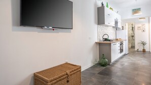 A modern kitchen with a flat-screen TV, white cabinets, and a large island. - Jardín: Cómodo y Luminoso Apartamento (Santa Cruz de Tenerife)