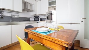 A modern kitchen with white cabinets, a wooden dining table, and yellow chairs. - Passons 4 - One Bedroom Apartment, Sleeps 2 (Udine)