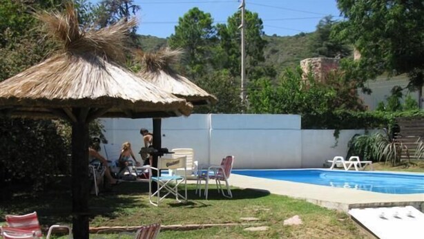 A backyard with a pool, a thatched-roof gazebo, and outdoor seating. - Hotel de la Cuesta (Villa Carlos Paz)