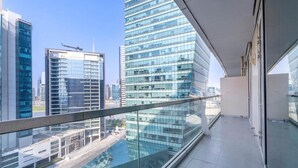Un edificio alto con fachada de vidrio, vistas despejadas del paisaje urbano circundante y un balcón con barandilla de cristal.