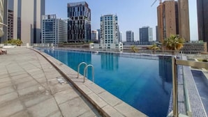 Una piscina en la azotea con vista a un paisaje urbano, rodeada de edificios modernos.