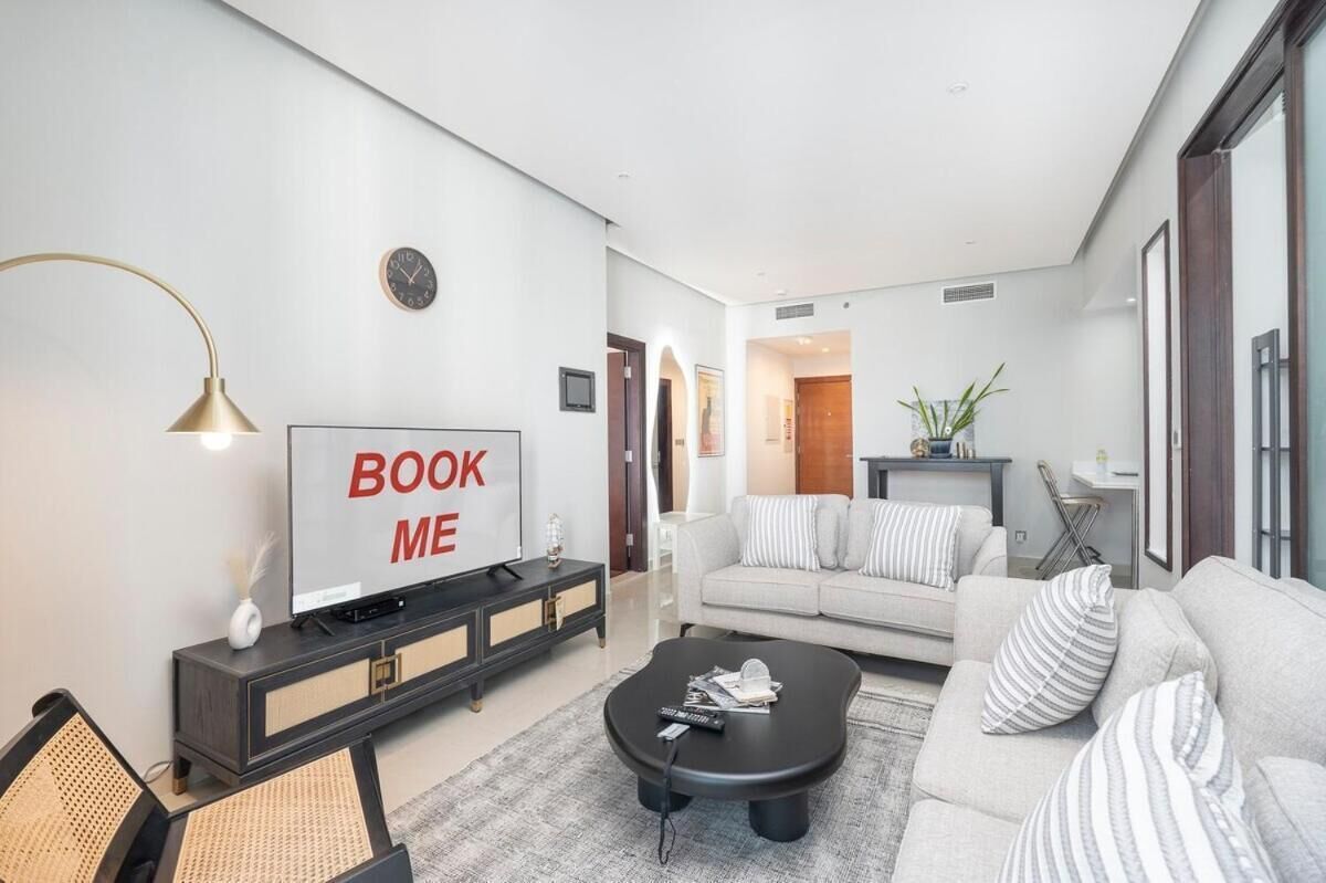 Ein modernes Wohnzimmer mit Fernseher, Sofa, Couchtisch und einem Schild mit der Aufschrift 'BOOK ME'.