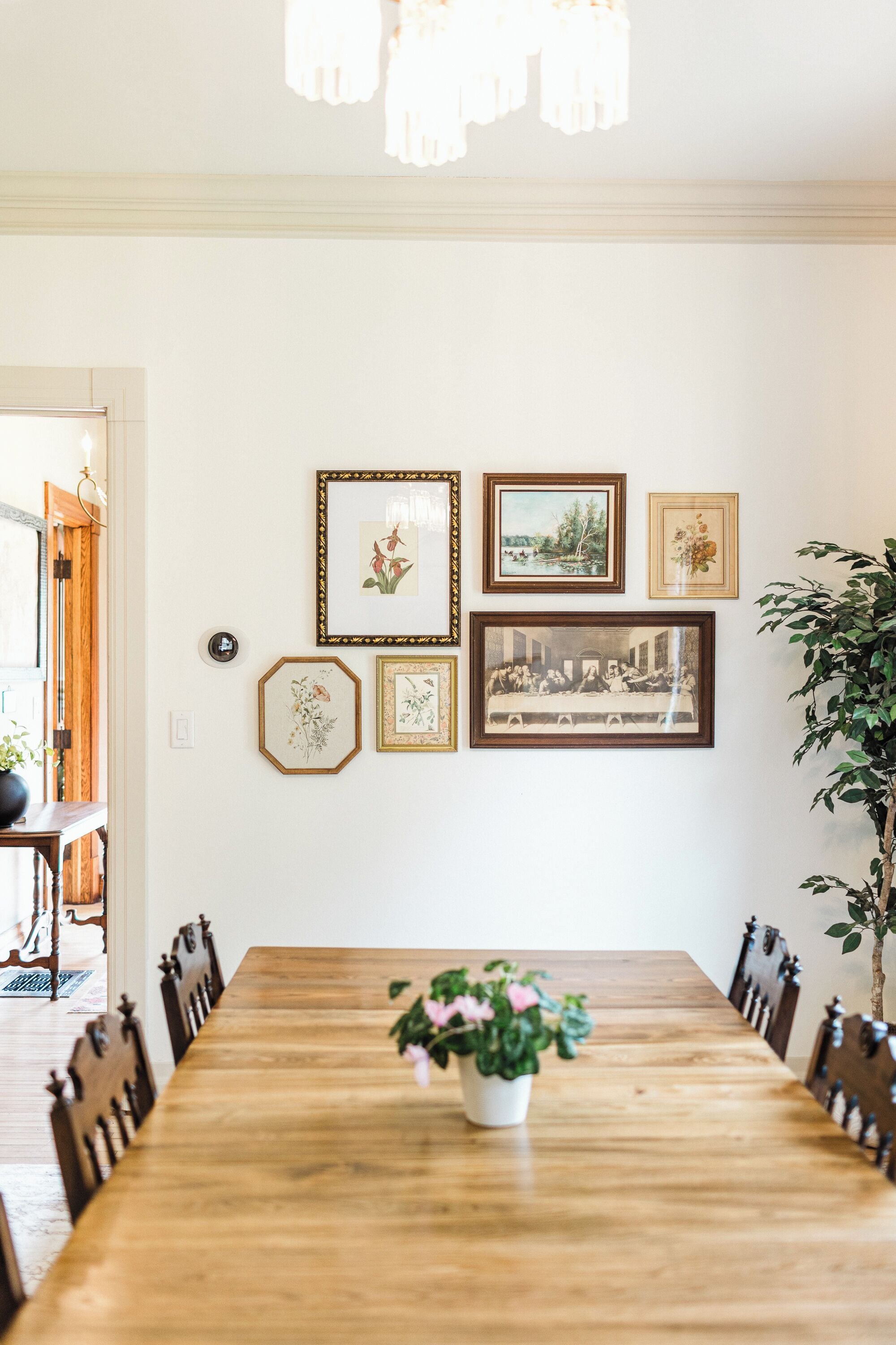 A dining room with a wooden table, chairs, and framed pictures on the wall.