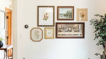 A dining room with a wooden table, chairs, and framed pictures on the wall.