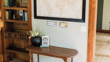 A wooden console table with a world map, a chandelier, and a bookshelf with books and decorative items.