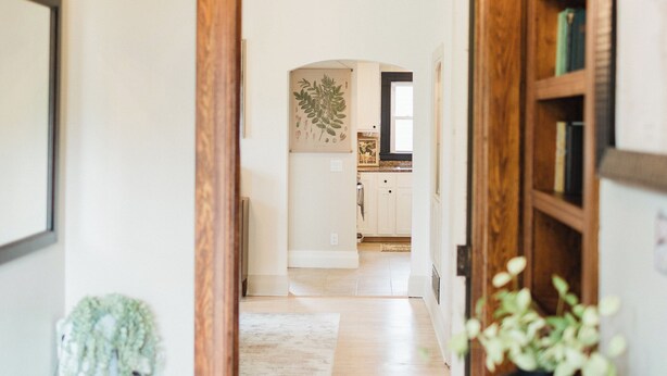 Un pasillo con una puerta de madera que da a una zona de cocina.