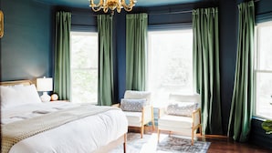 Un dormitorio con una cama grande, una mesita de noche, una silla y un candelabro.