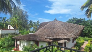 A thatched-roof house with a balcony, surrounded by lush greenery and palm trees. - BEAUTIFUL VILLA OPPOSITE THE BEACH AND IN THE CENTER OF SALY (Saly)