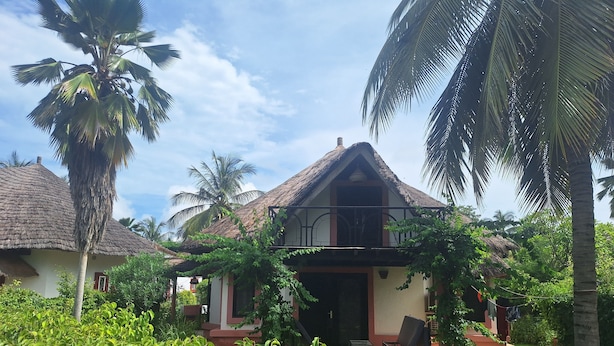 A house with a thatched roof, surrounded by lush greenery and palm trees. - BEAUTIFUL VILLA OPPOSITE THE BEACH AND IN THE CENTER OF SALY (Saly)