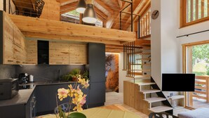 A modern kitchen with wooden beams, a black refrigerator, and a dining area with a table and chairs.
