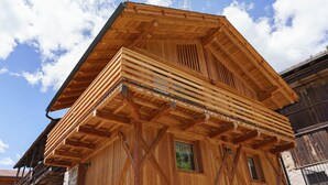 A wooden building with a sloped roof, a window, and a balcony.