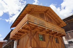 Un edificio de madera con techo inclinado, una ventana y un balcón.