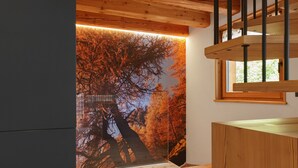 A wooden interior with a staircase, a window, and a wall with a tree mural.