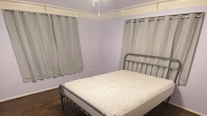A bedroom with a single bed, wooden flooring, and a ceiling fan.