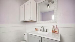 A bathroom with a white toilet, a sink with a mirror above it, and cabinets below.