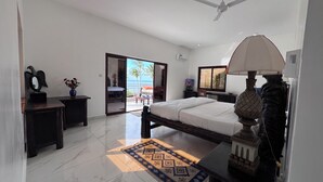 Un dormitorio con cama, mesita de noche, lámpara y vistas al exterior.