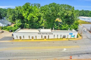 A building named 'The Light Building' with a flat roof, a parking lot, and a clear sky. - Walk to Downtown, King Bed, great for long stays (Spartanburg)