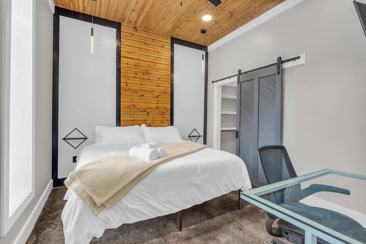 Una habitación de hotel moderna con una cama, una mesita de vidrio y un armario corredero.