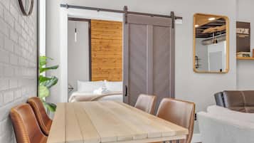 Un interior moderno con una mesa de madera, sillas de cuero, una puerta corredera estilo granero, un espejo y una planta.