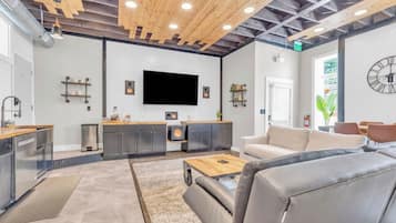 Un interior moderno con cocina, zona de estar y un televisor de pantalla plana grande.