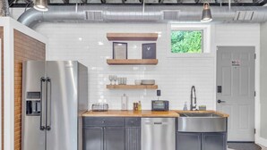 A modern kitchen with stainless steel appliances, wooden shelves, and a built-in window. - Walk to Downtown, King Bed, great for long stays (Spartanburg)
