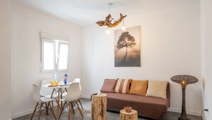 A modern living room with a dining area, a sofa, a coffee table, and a unique wooden floor lamp.