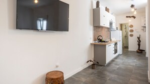 A modern kitchen with a flat-screen TV, white cabinets, and a central island.