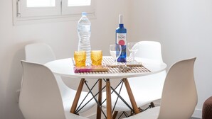 A round table with a white tablecloth, two chairs, a bottle of water, a bottle of Vina Taoro, and two glasses on the table.