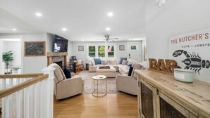 A spacious living room with a fireplace, comfortable seating, and a wooden bar area. - Recently renovated 3 bedroom (Falmouth)