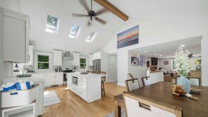 A spacious kitchen with white cabinetry, a central island, and a dining area with a wooden table and chairs. - Recently renovated 3 bedroom (Falmouth)